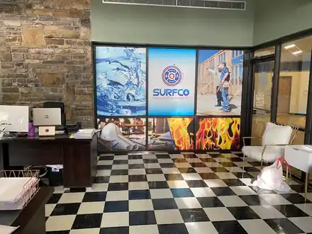 Office interior with a checkerboard floor, Surfco graphic wall panels and a desk