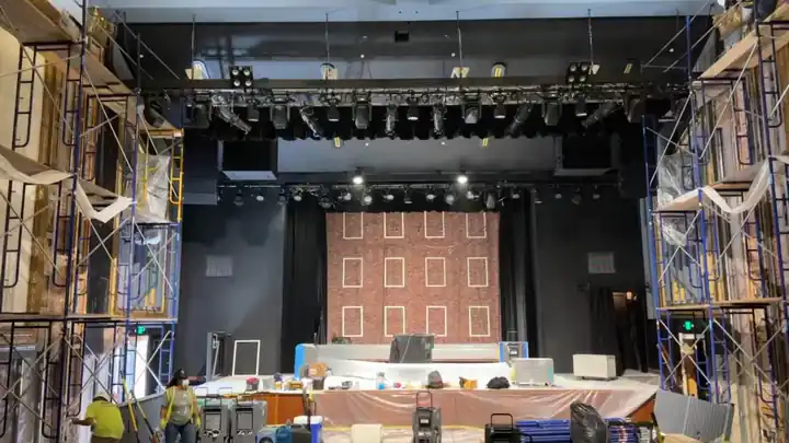 A theatre stage during a Surfco restoration: scaffolding up both side walls, plastic sheeting over the stage and drying equipment running