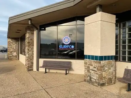 Office exterior with stone columns, a bench and the Surfco logo on the window