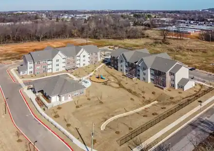 Aerial view of a multifamily project with several apartment buildings and a playground on a cleared lot