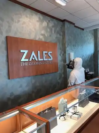 Tyvek-suited Surfco technician misting display cases under a Zales sign