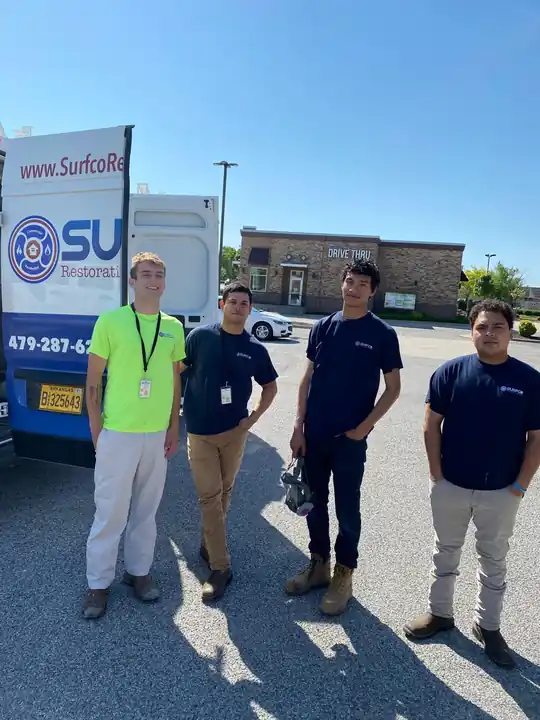 Four Surfco staff standing beside a Surfco van on a sunny lot